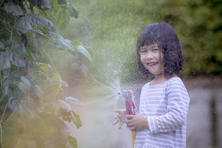 asian children playing water splashing frome a hose with happiness face in home gardenの写真素材