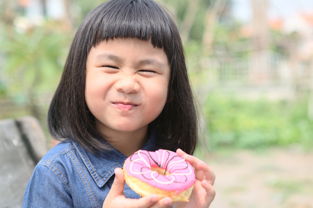 happiness face of asian children with sweet donut in handの写真素材