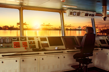 wheelhouse control board of modern industry ship approaching to harbor at night