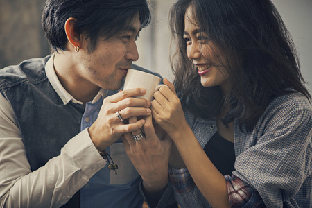 couples of asian younger man and woman happiness emotion with hot coffee cup in handの写真素材