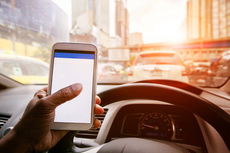 man driving car in urban traffic and touching  on smart phone application screen