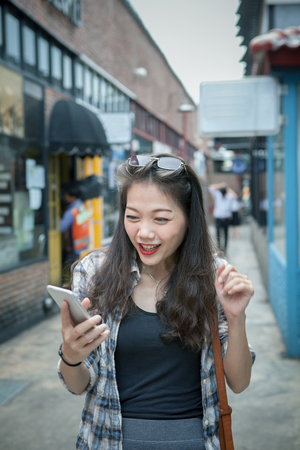 young asian woman reading message on smart phone and with happinessの写真素材