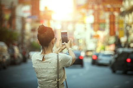 Woman tourist taking a photograph with smart phone in Yaowarat china town Bangkok Thailandの写真素材