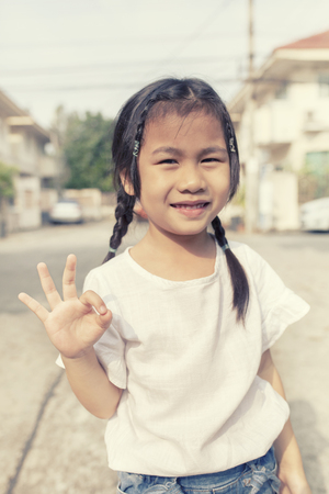 asian children hand sign all right with smiling face outdoorの写真素材