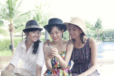 group of young asian woman friend watching on smart phone screen with toothy smiling face happiness emotionの写真素材