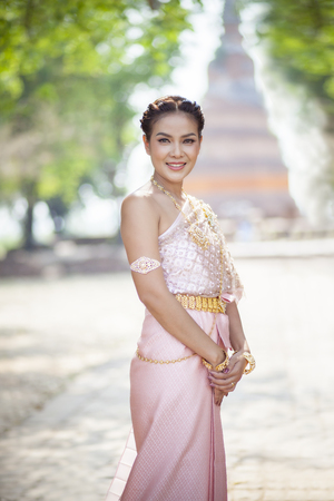 beautiful thai woman wearing old thai tradition clothes style holding bamboo wood umbrella with toothy smiling faceの写真素材