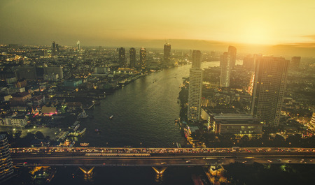 aerial view of sunset sky over chaopraya river and sathorn bridge in heart of bangkok thailand...
