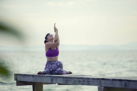woman playing yoga on wooded pier against plain sea backgroundの写真素材