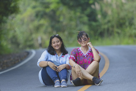 two generation of asian woman sitting on asphalt road in khao yai national park thailandの写真素材
