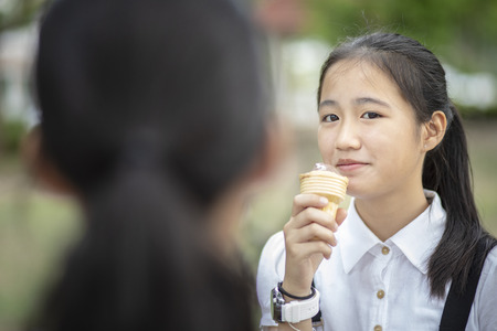 asian teenager eating icecream cone with happiness faceの写真素材