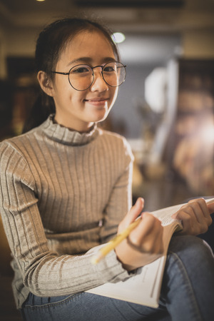 asian teenager reading a book with happiness emotion face in home living roomの写真素材
