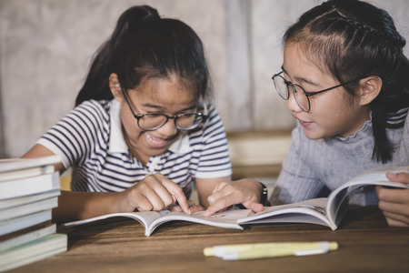 two asian student reading a school book with happiness emotionの写真素材