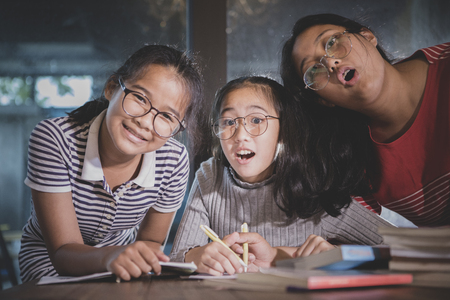 cheerful three asian teenager doing school work  in home living roomの写真素材