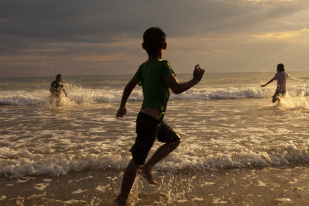 three chiodren playing on sea beachの写真素材