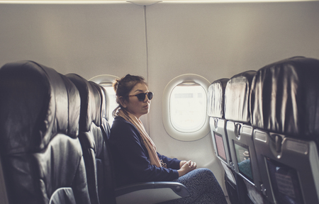 lonely asian woman sitting beside plane window use for traveling themeの写真素材
