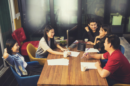 younger asian freelance team relaxing on working table in office meeting roomの写真素材