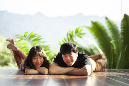 couples of younger asian man and woman lying with happiness face on home wood floorの写真素材