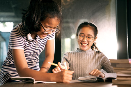 two asian girl laughing with happiness emotion doing school home work in living roomの写真素材