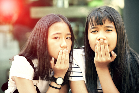 face of two asian teenager standing and looking to camera with eye contactの写真素材