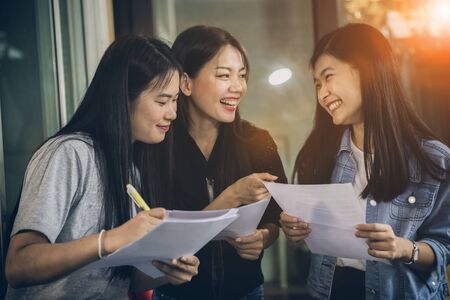 asian younger woman freelance talking with toothy smiling face in home officeの写真素材