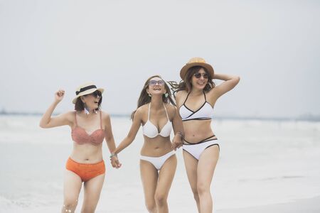three asian woman bikini relaxing on vacaton beachの写真素材
