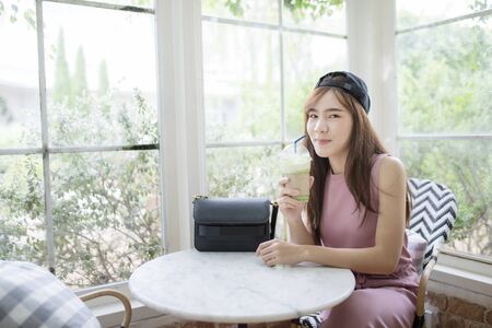 happiness smiling face of asian younger woman with cool bottle of green tea beverageの写真素材