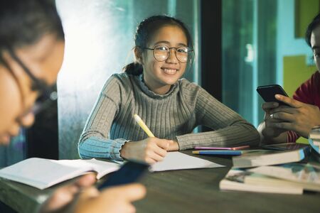 cheerful three asian teenager doing school work  in home living roomの写真素材