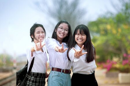 toothy smiling face of asian teenager group sign i love you by hand の写真素材