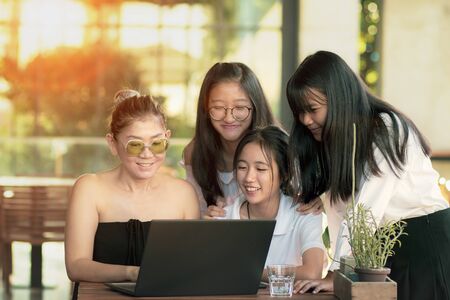 asian woman and teenager working on computer laptop in living roomの写真素材