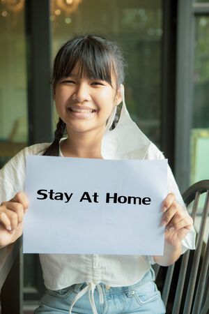 asian teenager social distancing covid anti campaign holding  stay at home paper pageの写真素材