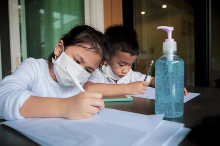 asian children wearing protection mask and class studying at home living roomの写真素材