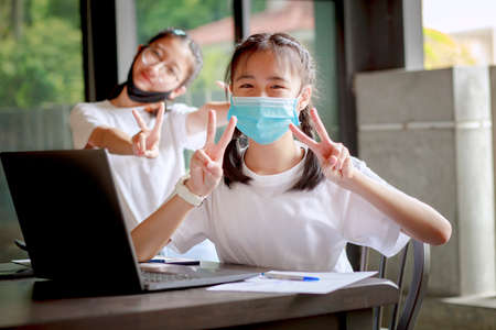 asian teenager wearing protection mask working on computer laptop at homeの写真素材