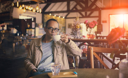asian man drinking hot coffee in cafeの写真素材
