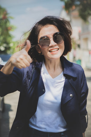 woman toothy smiling face show right thumb outdoorの写真素材