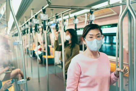 asian woman wearing protection mask standing in underground trainの写真素材