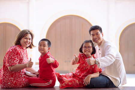 asian family wearing red chinese suit hand sign okay against chinese wall backgroundの写真素材