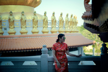 asian pretty woman wearing red chinese suit standing outdoorの写真素材