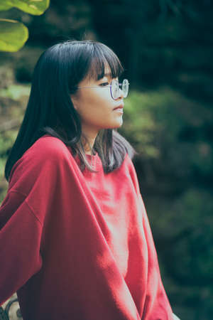 portrait of asian teenager wearing eyeglasses standing outdoorの写真素材