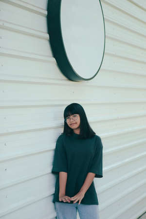 portrait of asian teenager standing against white wall