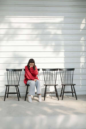 asian teenager sitting on wood desk against white wall background