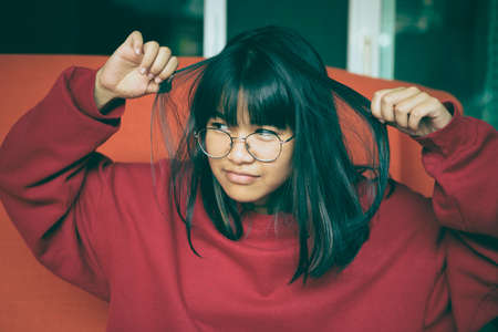 portrait cheerful asian teenager holding touching on hair