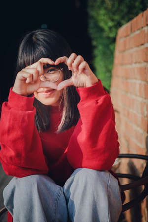 portrait of cheerful asian teenager making finger like a heart sign
