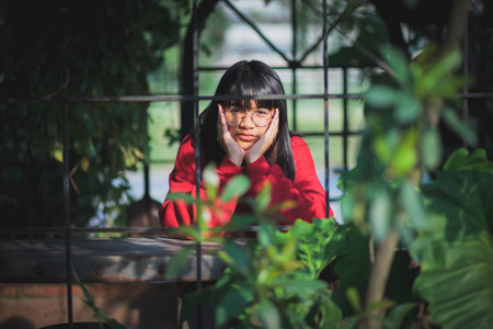 asian teenager wearing red sweater  sitting  outdoor