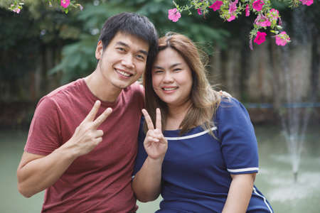 asian couples hand sign victory with happy smiling faceの写真素材