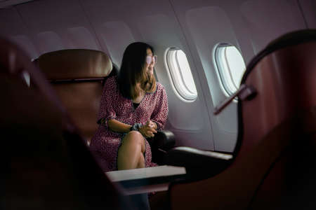 woman sitting beside plane window and lookint through out with smiling face