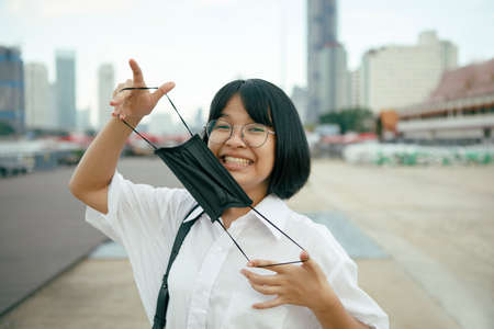 cheerful asian teenager with protection face mask in handの写真素材
