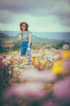 happy woman standing in beautiful blooming flower fieldの写真素材