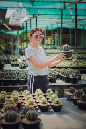 woman relaxing in succulent garden holding melocactus pot in handの写真素材