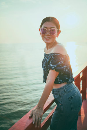 portrait beuatiful woman standing against sunset light  on beach pier