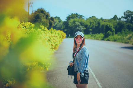 portrait of beautiful woman wearing sunglasses standing on road side